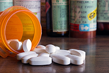 A spilled bottle of opioid pills on a table. Other pill bottles are visible in the background.